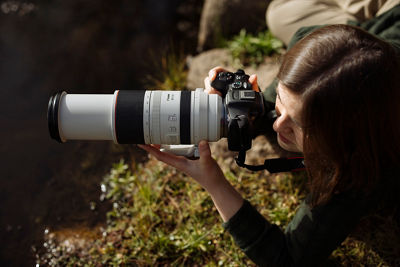 A photographer, outdoors and captured from above, using a Canon EOS R7 and Canon RF 100-500mm F4.5-7.1 L IS USM lens.